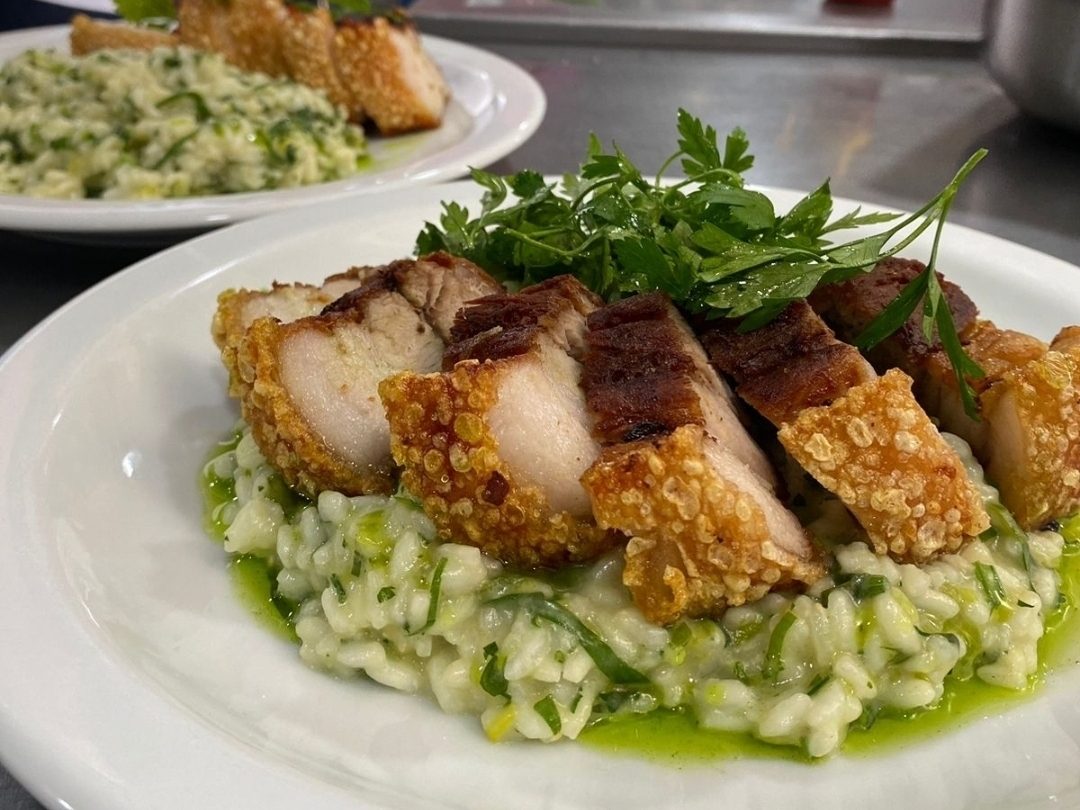 Risoto cítrico com alho-poró, torresmo e saladinha de ervas.